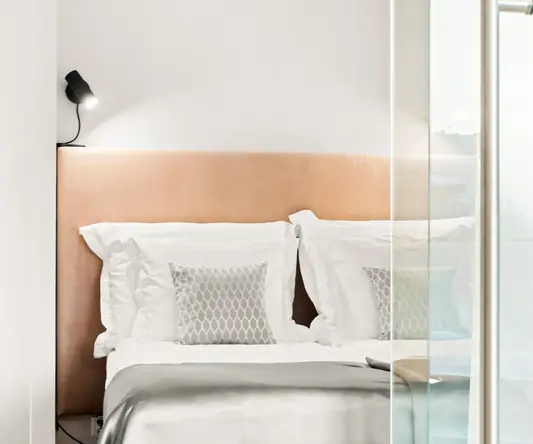 a bed with pillows and a light on the wall
