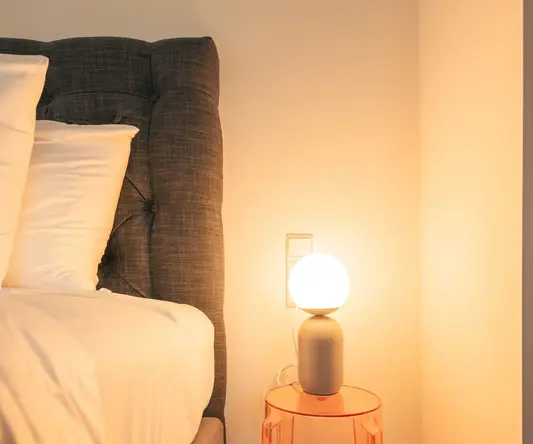 a lamp on a table next to a bed