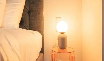 a lamp on a table next to a bed