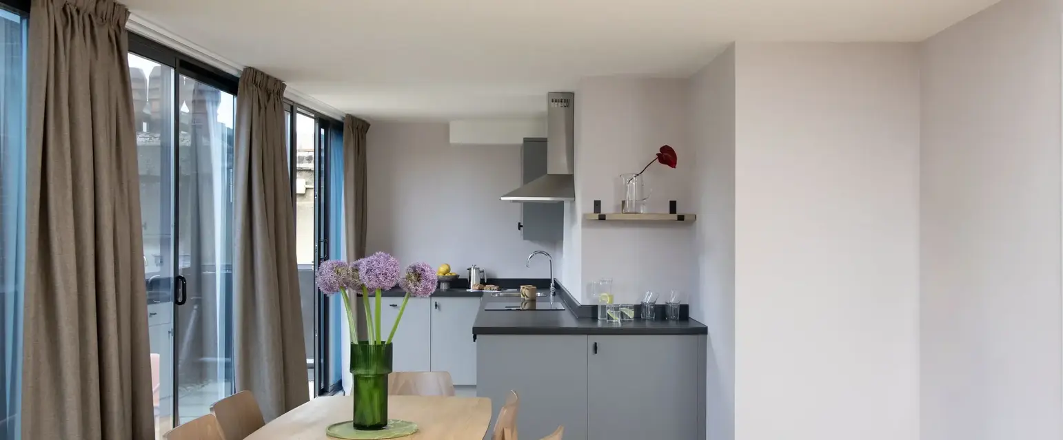 a dining table with chairs in a room with windows