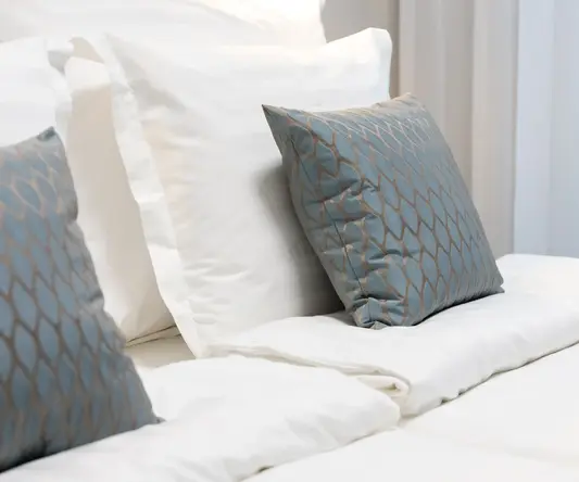 a bed with pillows and a light on the wall