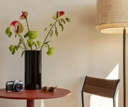 a vase with flowers and sunglasses on a table