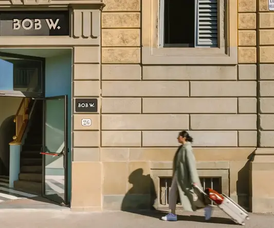 a woman walking with luggage in front of a building