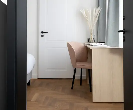 a white door with a pink chair and a desk