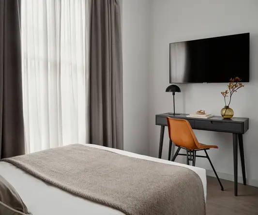 a room with a bed and a desk and a tv