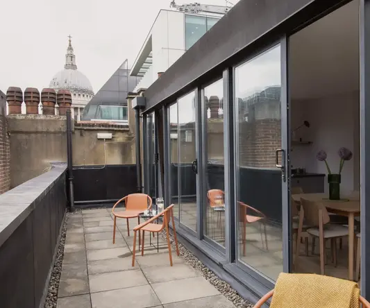 a patio with chairs and table on a rooftop