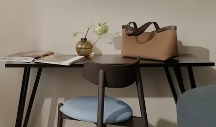 a chair and a table with a vase of flowers and a purse