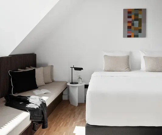 a bed with pillows and a bench in a room