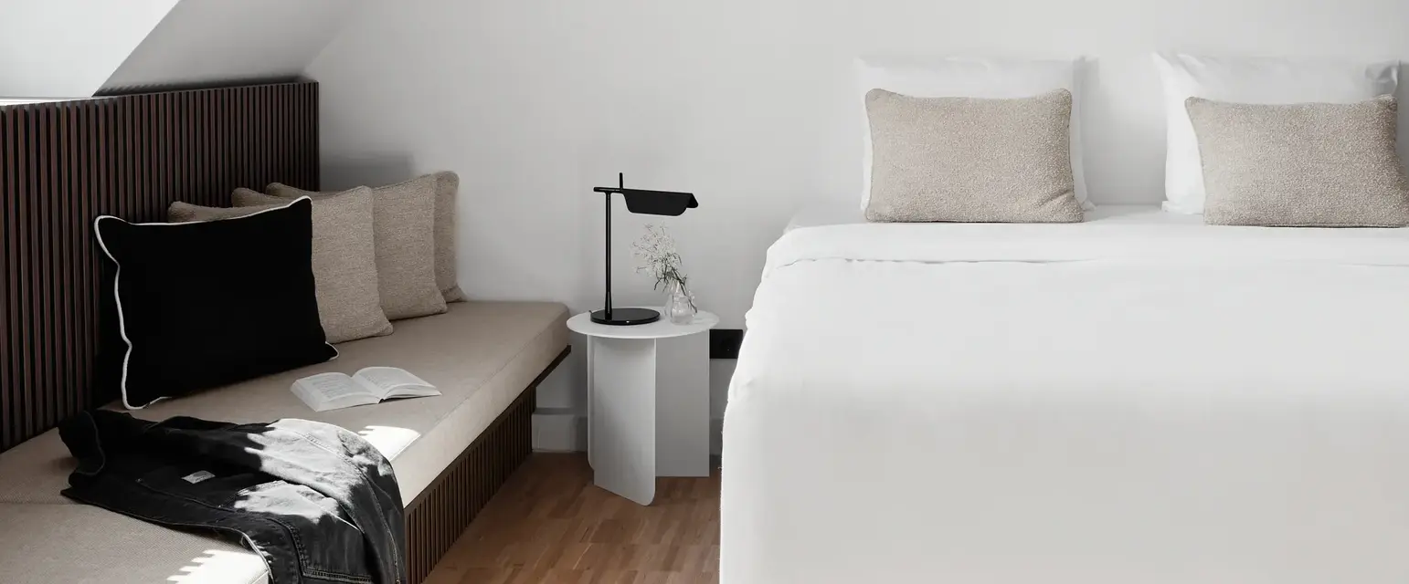 a bed with pillows and a bench in a room