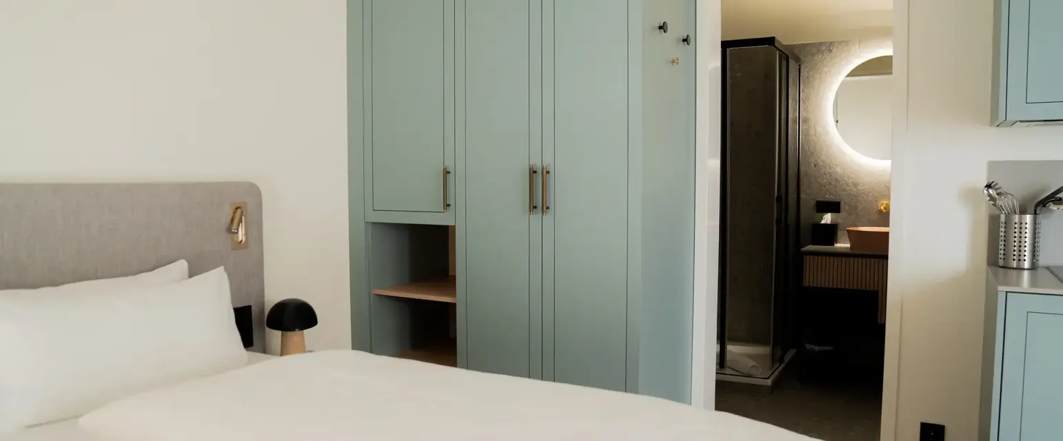 a bed with white sheets and a blue wardrobe