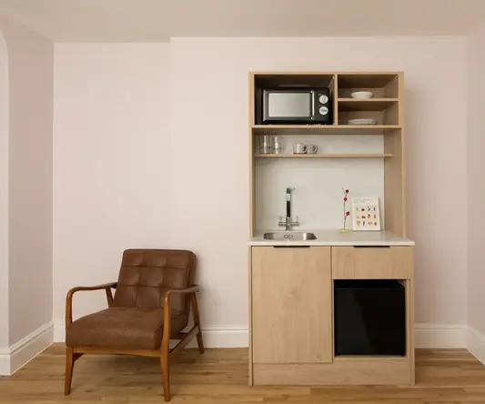 a small kitchen with a microwave and a chair