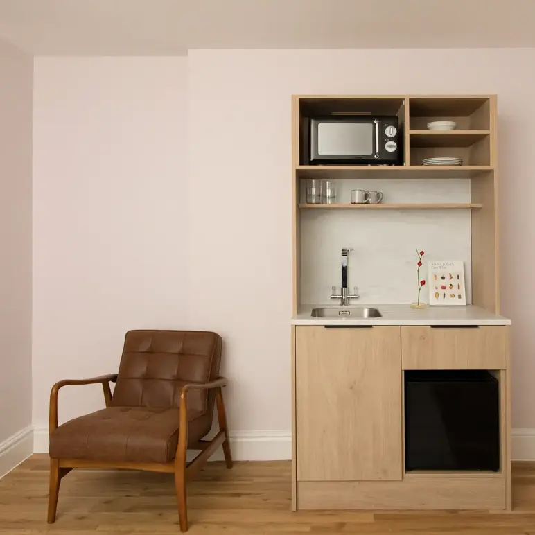 a small kitchen with a microwave and a chair