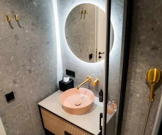 a sink with a round mirror above it