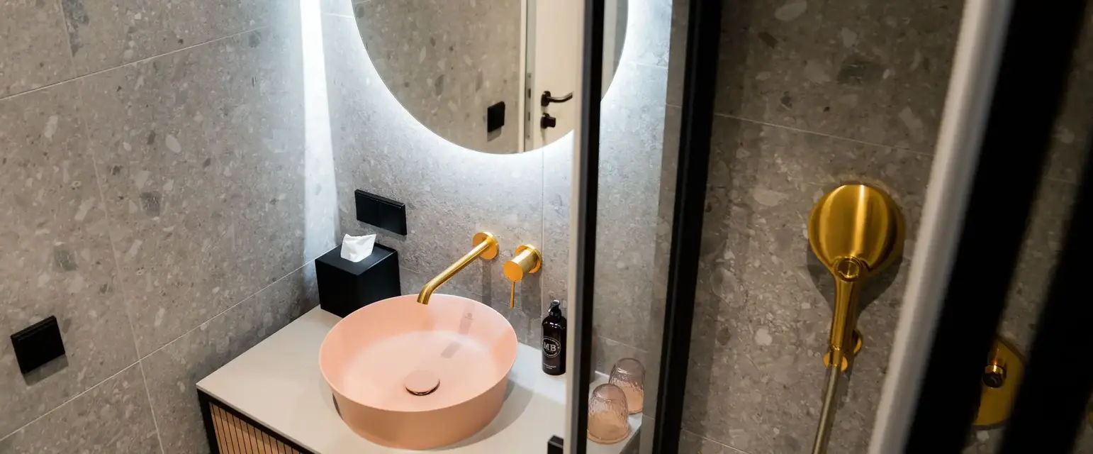 a sink with a round mirror above it