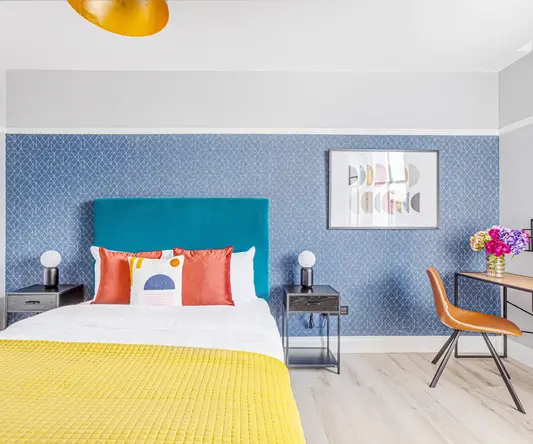 a bed with a yellow blanket and a blue wallpaper