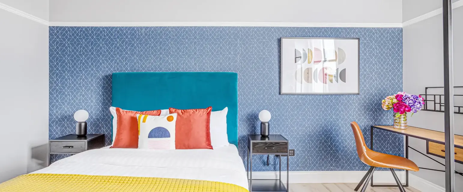 a bed with a yellow blanket and a blue wallpaper