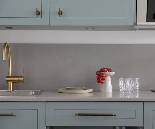a kitchen counter with a bowl of tomatoes and glasses