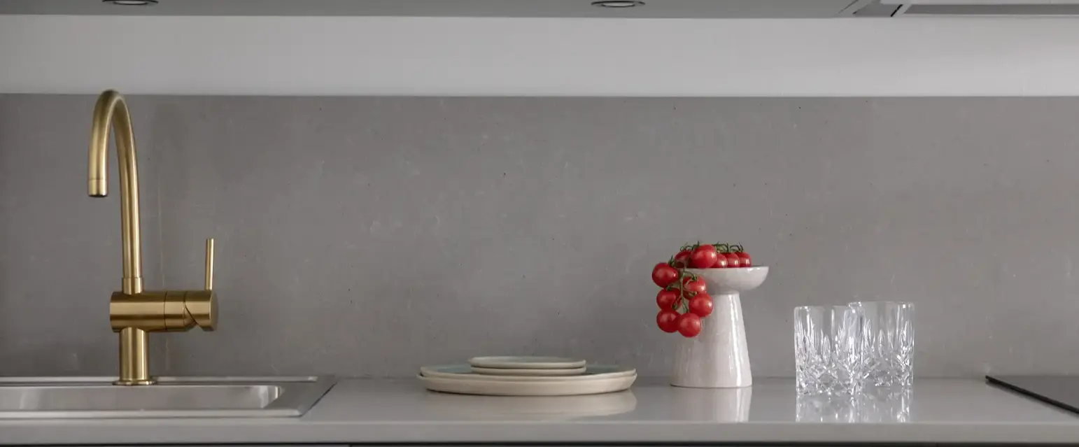 a kitchen counter with a bowl of tomatoes and glasses