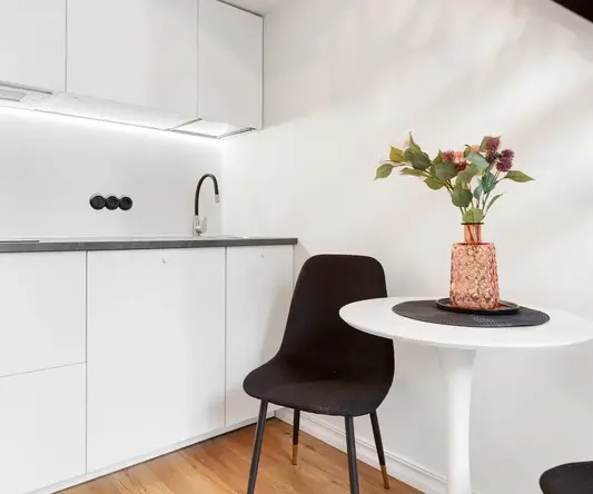 a white kitchen with a table and a vase of flowers