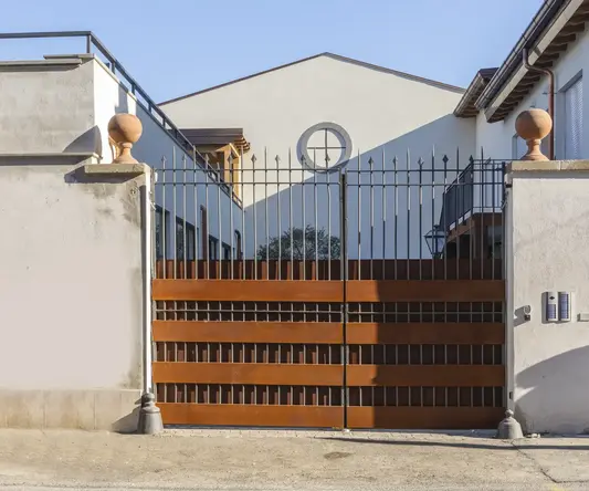 a gated driveway with a house behind it