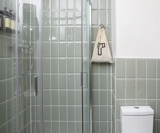 a shower with glass doors and a bag on the wall