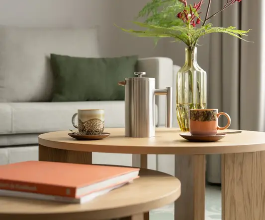 a coffee table with a vase of flowers and a coffee pot on it