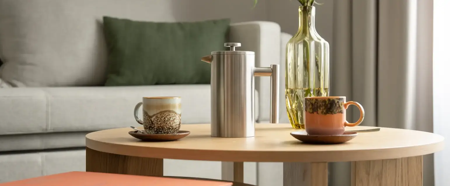 a coffee table with a vase of flowers and a coffee pot on it