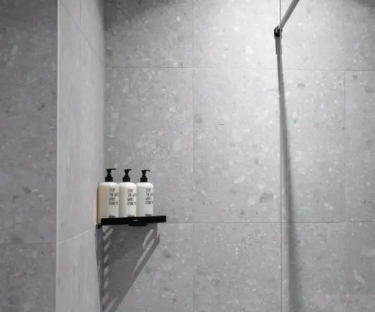 a shower with a couple of white bottles on a shelf
