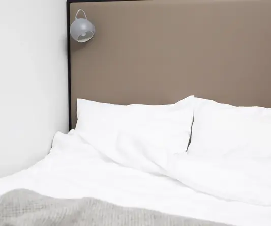 a bed with a lamp on the wall