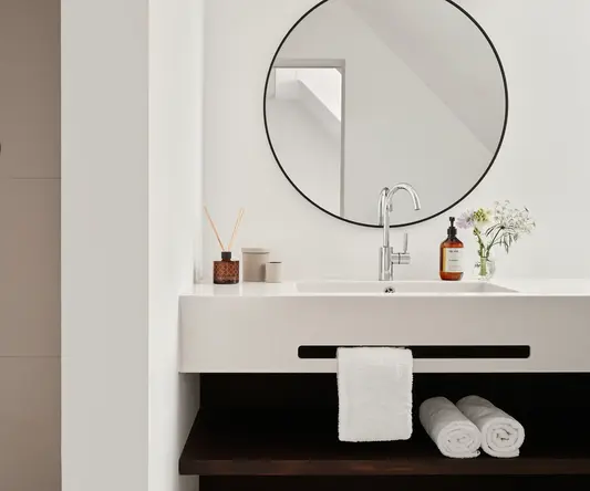 a bathroom sink with a round mirror