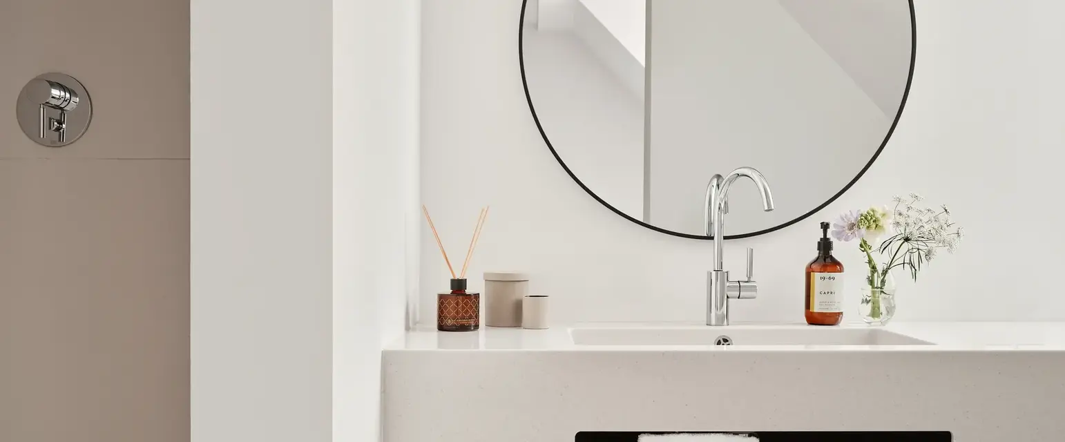 a bathroom sink with a round mirror