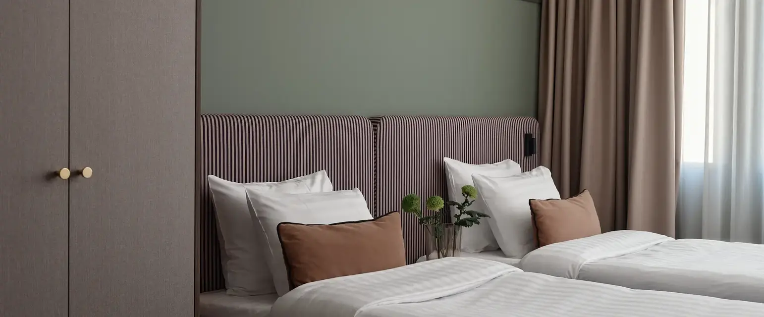 a bed with pillows and a vase of flowers on it