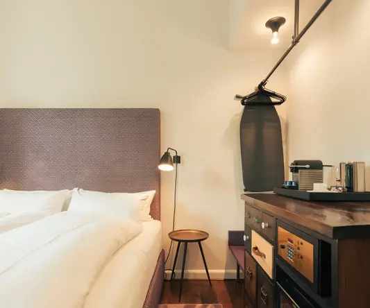 a bed with a white blanket and a brown headboard