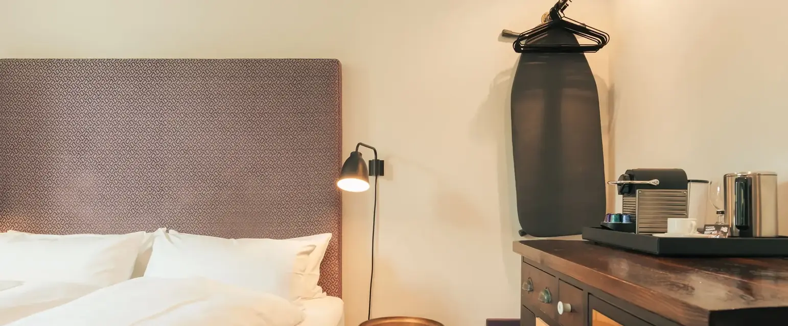 a bed with a white blanket and a brown headboard