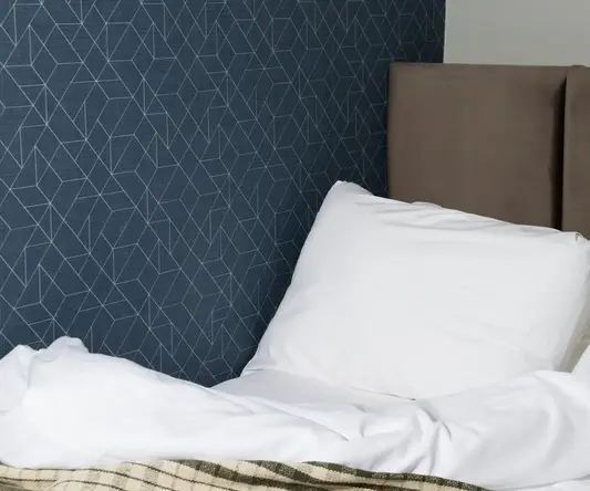 a bed with a white pillow and a brown headboard