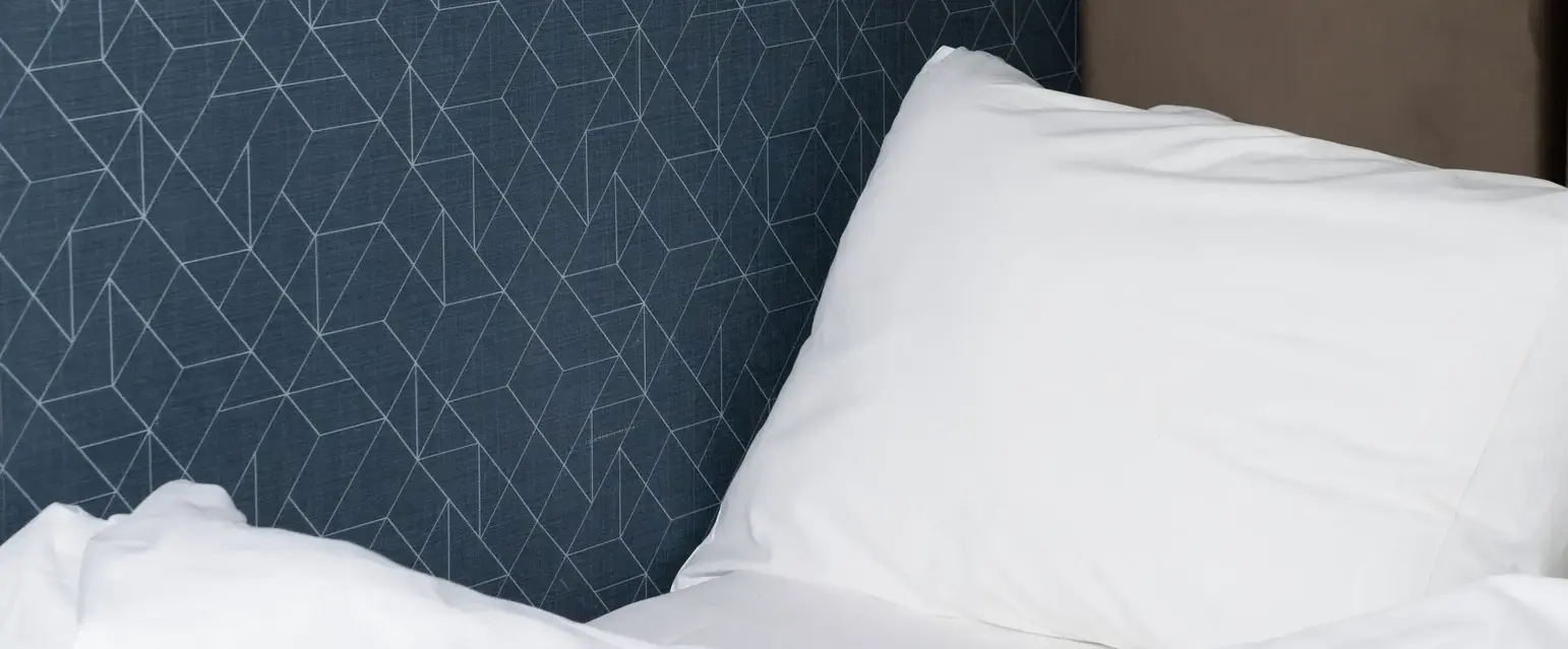 a bed with a white pillow and a brown headboard