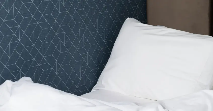 a bed with a white pillow and a brown headboard