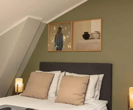 a bed with pillows and a lamp on the side