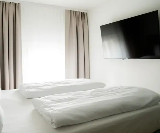 a bed with white sheets and a flat screen tv