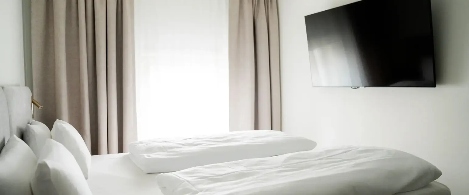 a bed with white sheets and a flat screen tv