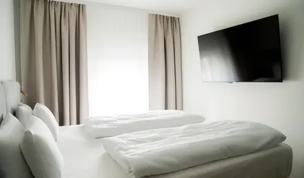 a bed with white sheets and a flat screen tv