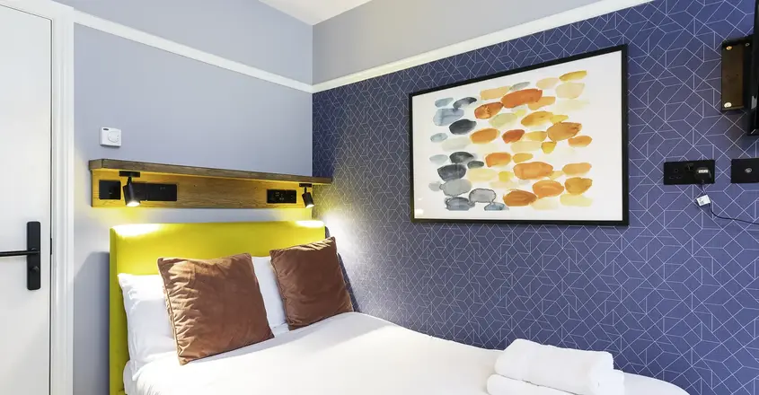 a bed with towels and a painting on the wall