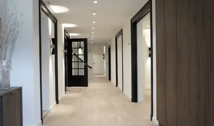 a hallway with black doors and wood floors