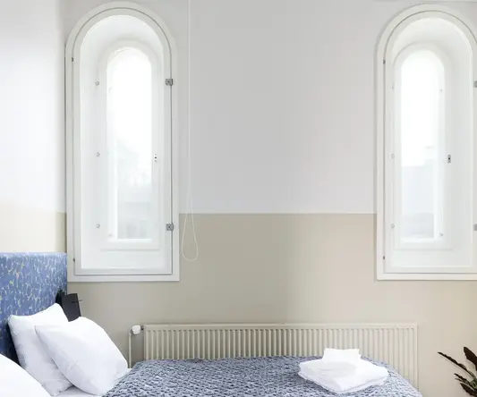 a bed with a blanket and a plant in front of it