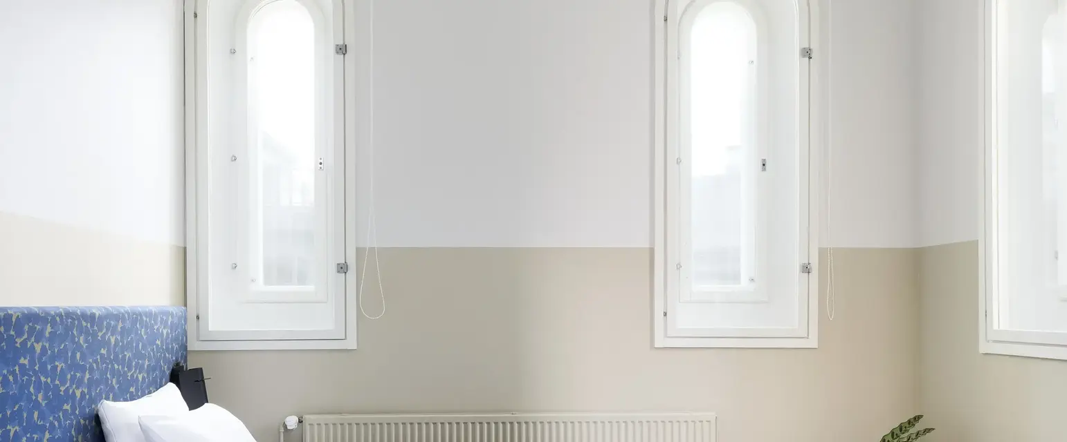 a bed with a blanket and a plant in front of it