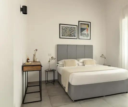 a bed with a headboard and a table with art on the wall