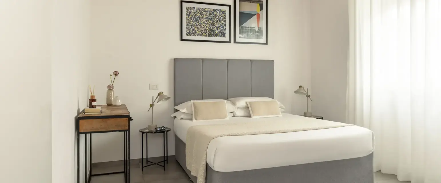 a bed with a headboard and a table with art on the wall