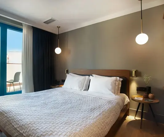 a bed with white sheets and a lamp next to a glass door