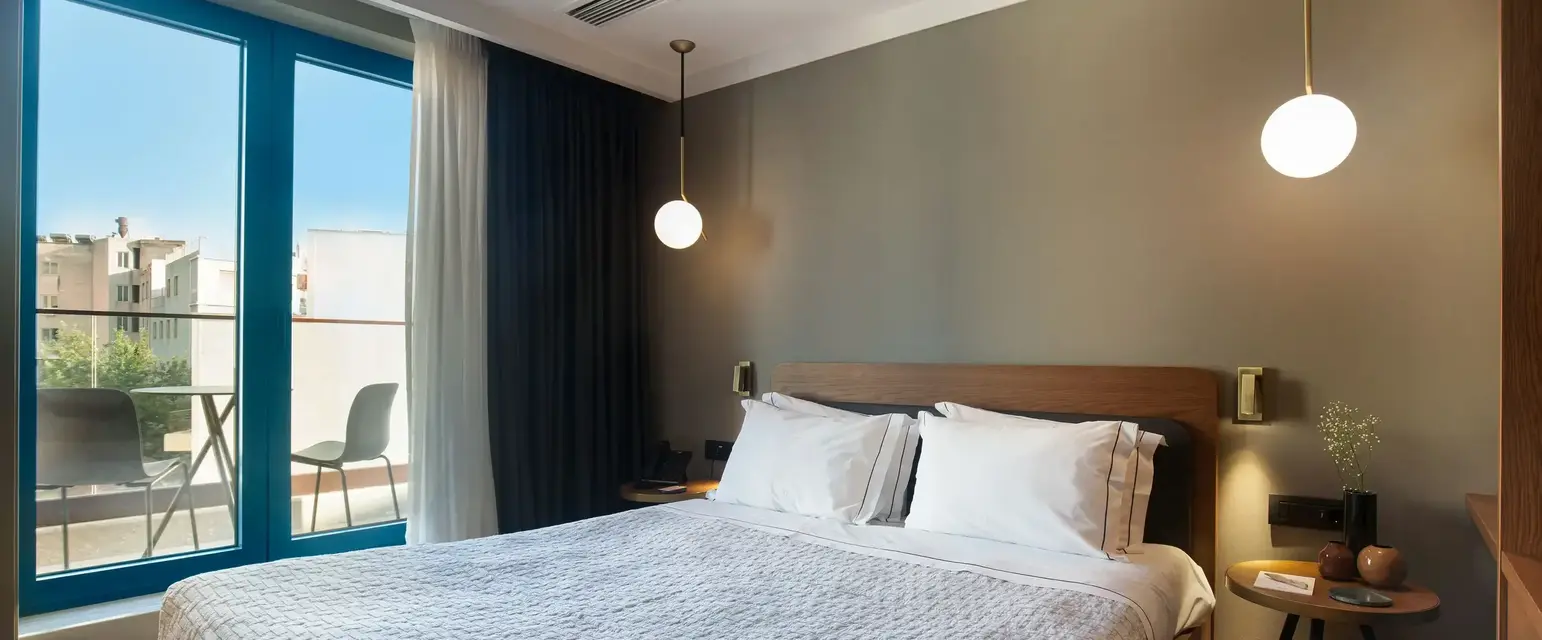 a bed with white sheets and a lamp next to a glass door