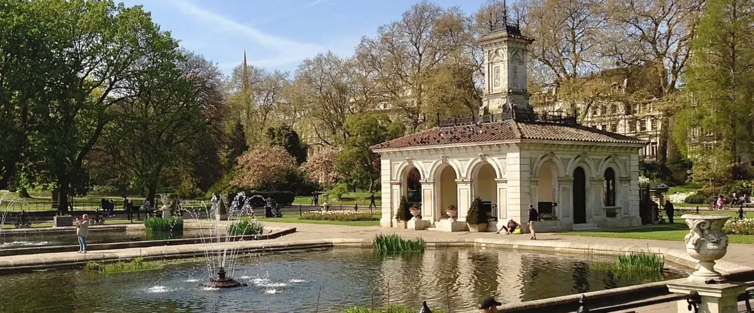 a man sitting on a bench in front of a pond with a fountain